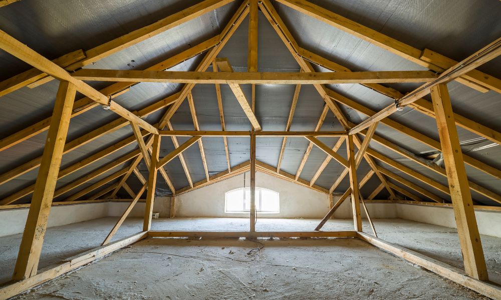 Exposed wooden rafters and roof decking inside an attic, where homeowners can look for clues about previous roof replacements.